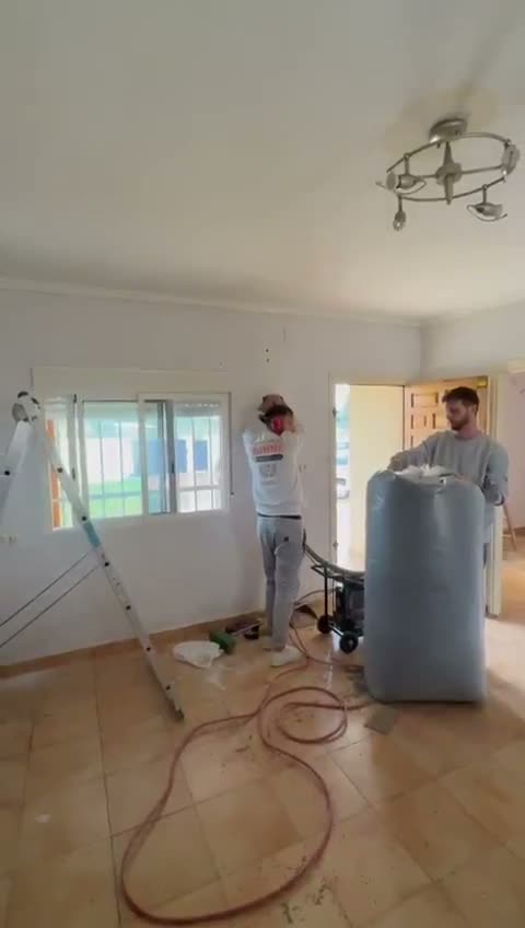 Dos operarios de Munné insuflando aislamiento en la cámara de aire de una vivienda